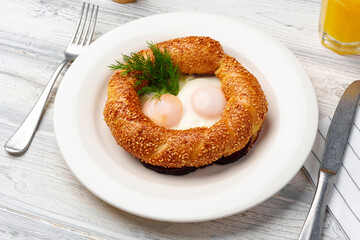 Turkish bagel simit and fried eggs on plate