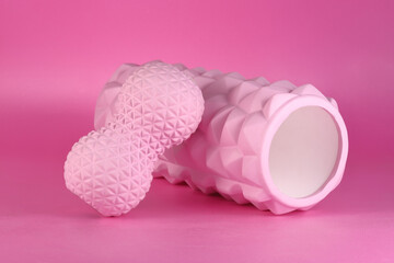 Two pink foam massage rollers for stretching and yoga on pink background. Fitness equipment.