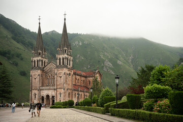 Fototapeta na wymiar People walking around of a catholic sanctuary beside the mountains