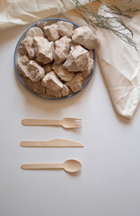 White clay stones with a wooden fork, spoon and knife on a white background