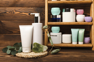 Tubes with cream on the background of a brown tabletop in the bathroom. Shelf with cosmetics. Face and body skin care. Moisturizer, toner and serum. Beauty concept. Place for text. Copy space.