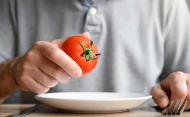 Minimalist delight: male hand holding a ripe tomato