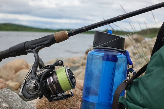 Kiiruna, Sweden - July 18, 2022: Backback, water bottle with filter and fishing tackle by Lainio river in Swedish Lapland on overcast summer day.