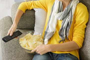 woman with bowl of chips and tv remote control