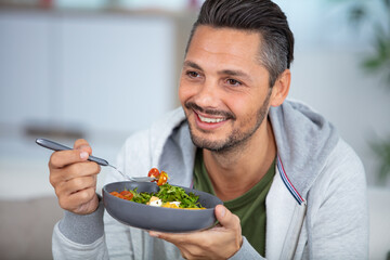 young man eating a healthy salad - Powered by Adobe