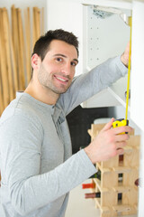 handyman measuring a wardrobe in a new house