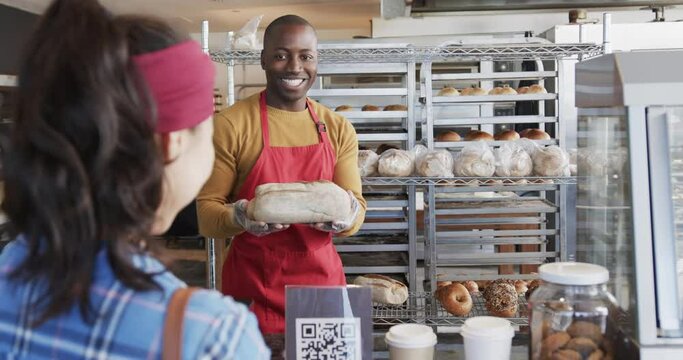 Diverse worker and customer offering fresh bread in bakery in slow motion