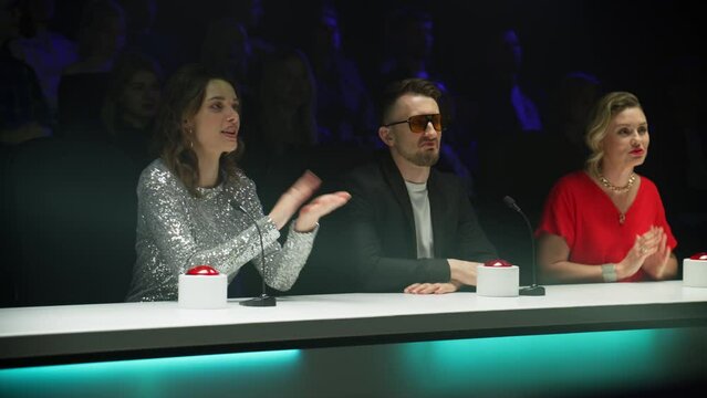 Portrait of celebrity judges enjoying the audition performed by talent on stage during the recording of a broadcast TV television talent show 