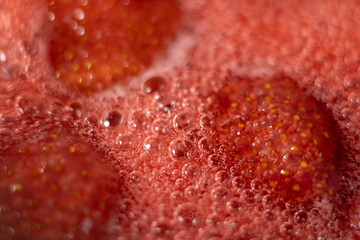 Pink foam for strawberry jam. Strawberries are boiled in a pot with sugar. The most delicious homemade strawberry jam. Soft selective focus on foam. An abstractly shaped picture with a partially shape
