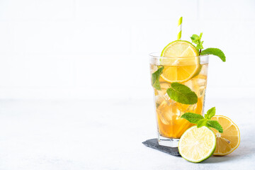Iced tea. Black tea with lemon, lime, mint and ice. Cold lemonade, summer drink, white background.