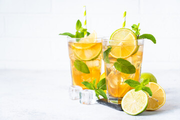 Iced tea. Black tea with lemon, lime, mint and ice. Cold lemonade, summer drink, white background.