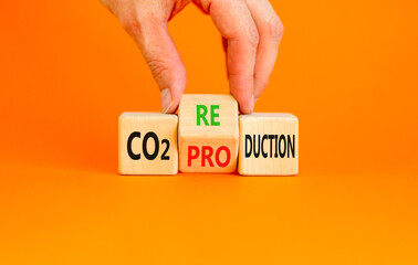 CO2 production or reduction symbol. Concept word CO2 production reductionon a wooden block on a beautiful orange background. Businessman hand. Business ecological and CO2 changes concept. Copy space.