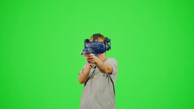 The woman shooting in virtual reality on chroma key green screen background.The girl wearing VR headset gaming in virtual reality war game.Concept war game VR headset leisure activity virtual reality
