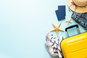 Suitcase, passports, hat and summer cloth on blue background. Happy Holidays, travel concept. Flat lay image.