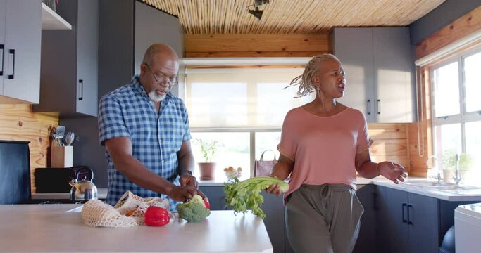 Senior african american couple unpacking groceries in kitchen, slow motion