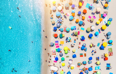 Aerial view of colorful umbrellas on sandy beach, swimming people in blue sea at sunset in summer. Sardinia, Italy. Tropical landscape with clear azure water. Travel and vacation. Top down drone view - obrazy, fototapety, plakaty