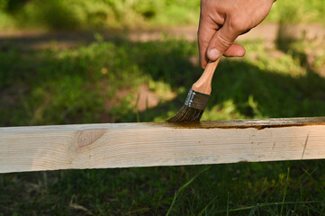 Painting protective paint and varnish coating on timber at outdoors.