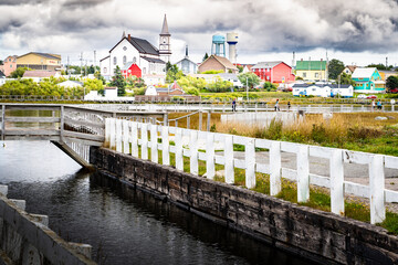 Wooden boardwalk along Old Bay Pond with a historic church landmarks and water towers overlooking the town of Bonavista Newfoundland Canada.