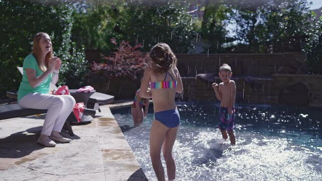 Kids splash around in a swimming pool while mom watches