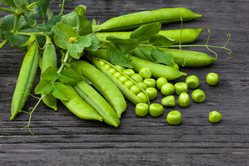 pods and grains of fresh green peas on a dark wooden background