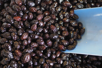 slices black olives with spoon in a bowl ,