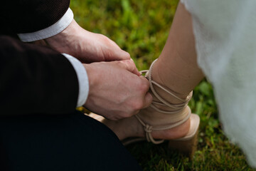 Groom tying shoelace of bride's sandals. Wedding ceremony element.