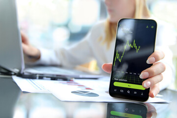 Businesswoman using a mobile phone for buying a crypto online in the office
