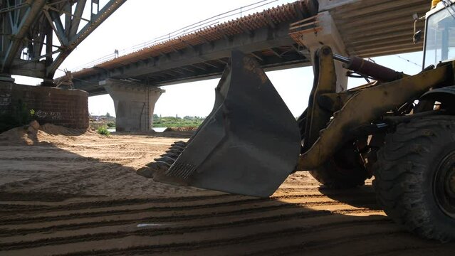 wheel loader works on the construction of new transport bridge across the river