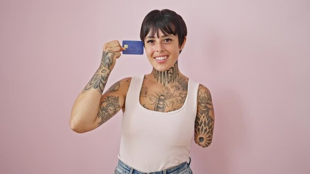 Hispanic woman with amputee arm smiling confident holding credit card over isolated pink background
