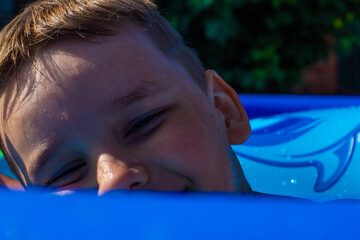Laughing child on an inflatable ring in the pool in summer. Child boy rejoices in cool water on a...