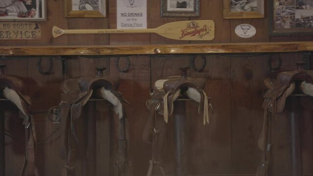 This panning video shows a row of saddle barstools at a western bar.