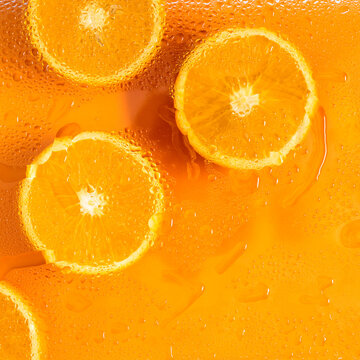 Orange slices with water drops under glass, summer lemonade, cocktail, orange drink. Flat lay, top view