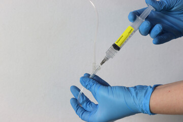 Profissional wearing gloves holding a ketamine syringe drug with liquid and injecting the drug in the intravenous acess.