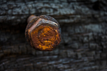 Rusty nut on stud with backing washer against a charred wooden background