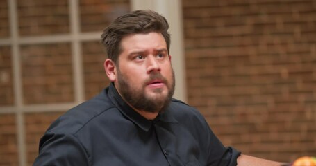 Bearded man reacts with opposition to a coworker in a meeting