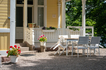 Swedish traditional yellow wooden summer house with outdoor white furniture at the entrance