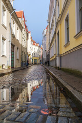 Fototapeta na wymiar Wet cobblestones after rain on a narrow street in the old town of Tallinn, Estonia. Cozy street in Tallinn