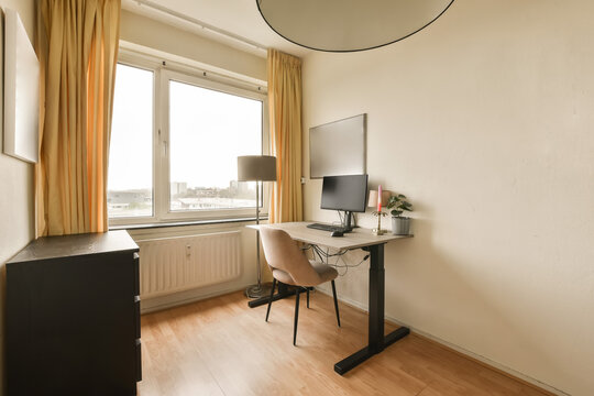 a small room with a desk, chair and television set up in front of a large window overlooking the city