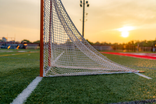 Dramatic late afternoon photo of a lacrosse goal on a synthetic turf field.	