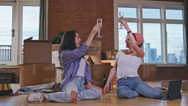 Two women cheers with champagne after moving into an urban loft