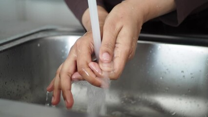 women washing hand in kitchen at home.