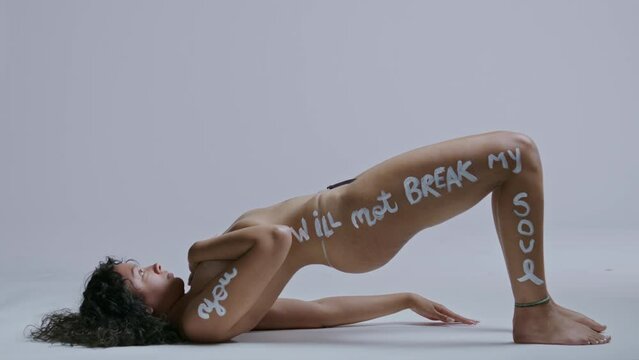 Mixed race woman lifts her body off the ground to reveal body painted saying
