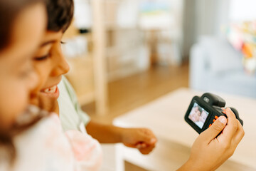 Smiling siblings using a kid camera taking photo of parents
Toddler using Toy Camera taking photo of parents