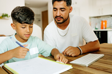 Homeschooling and freelancing. Happy child son giving high five to mother while doing homework or studying together at home, sitting at kitchen table with books and laptop