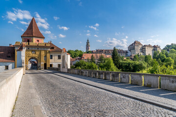 Fototapeta na wymiar Cesky Krumlov yellow city wall gate with bridge over the moat, below the Gothic castle