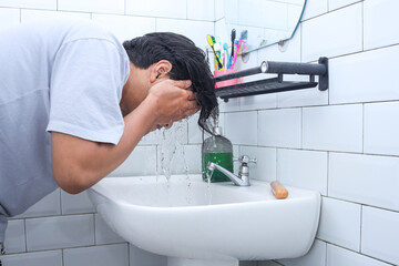 Side view man washing his face in bathroom, facial treatment in sink.  Men beauty skincare lifestyle.