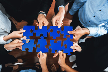 Top view multiethnic business people holding jigsaw pieces and merge them together as effective...