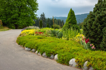 Walkway in flower garden in summer time. Colourful Flowerbeds in a good care maintenance landscapes and asfalt walkway