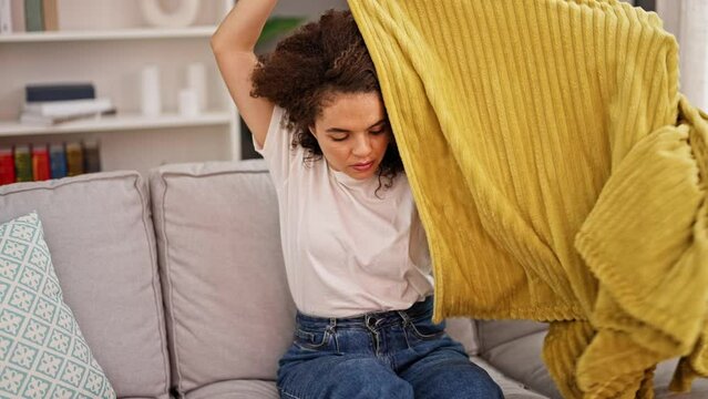Young beautiful hispanic woman feeling cold covered with blanket at home