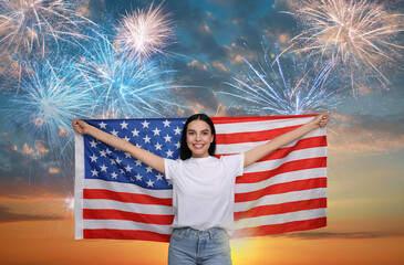 4th of July - Independence day of America. Happy woman holding national flag of United States against sky with fireworks